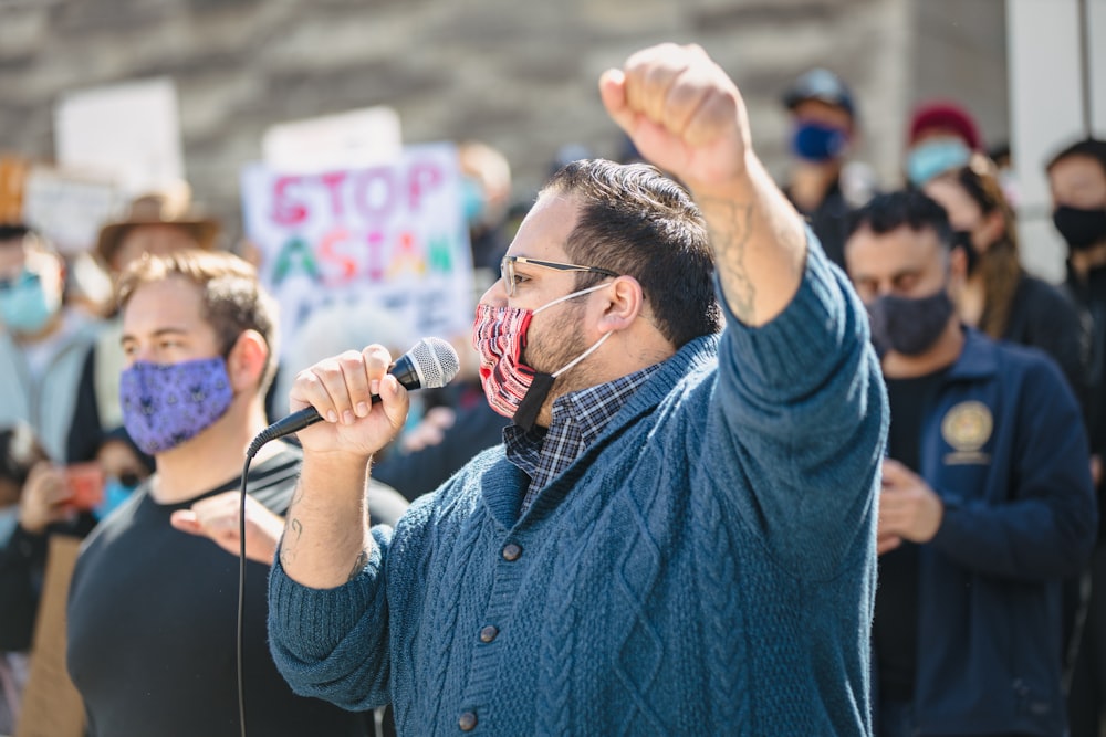 man in blue dress shirt holding microphone