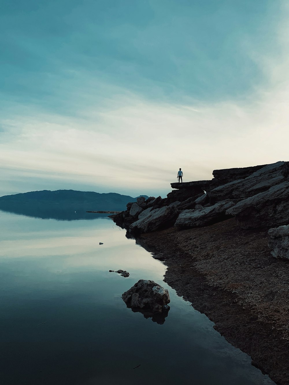 person standing on rock formation near body of water during daytime