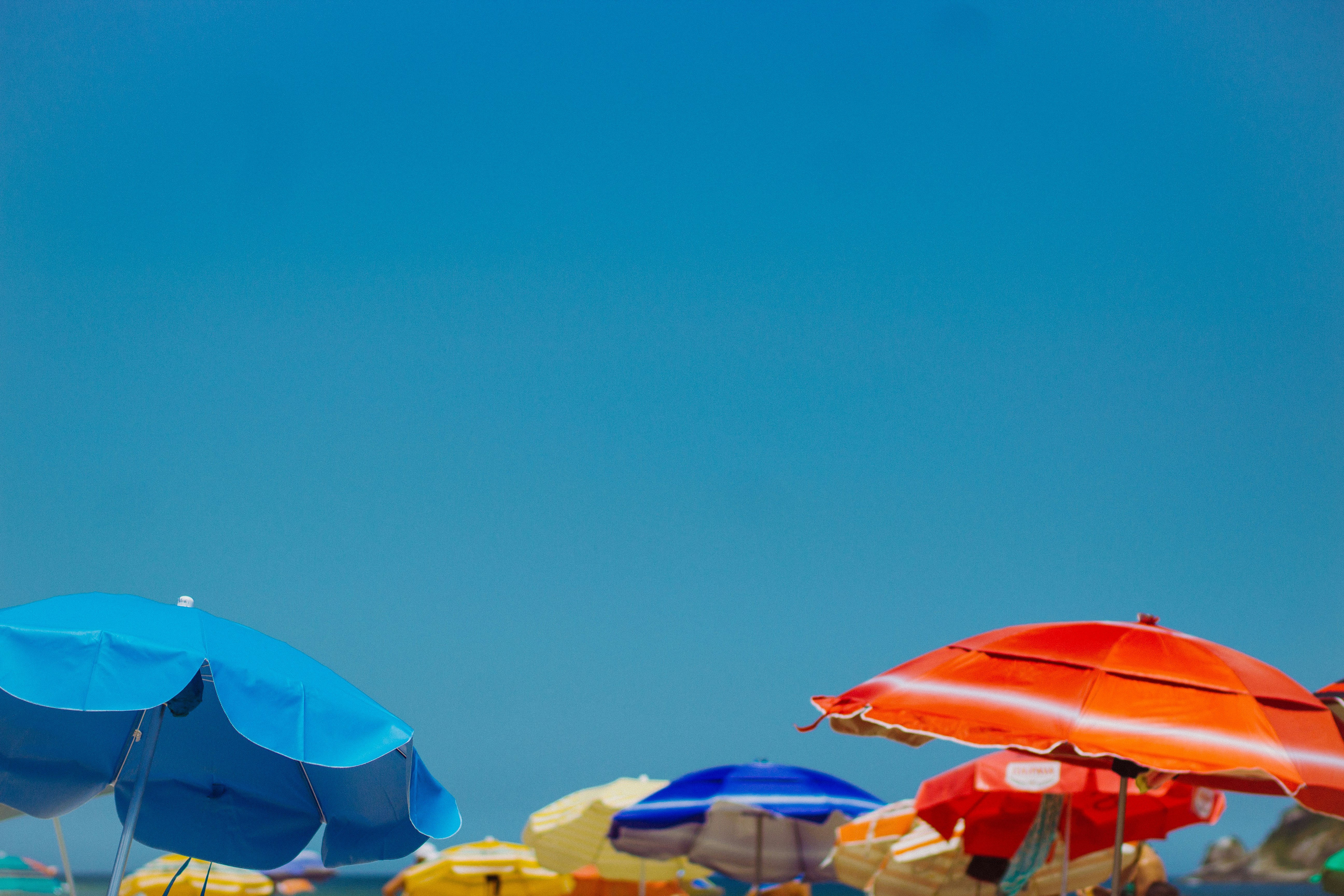 blue and red umbrellas on beach during daytime