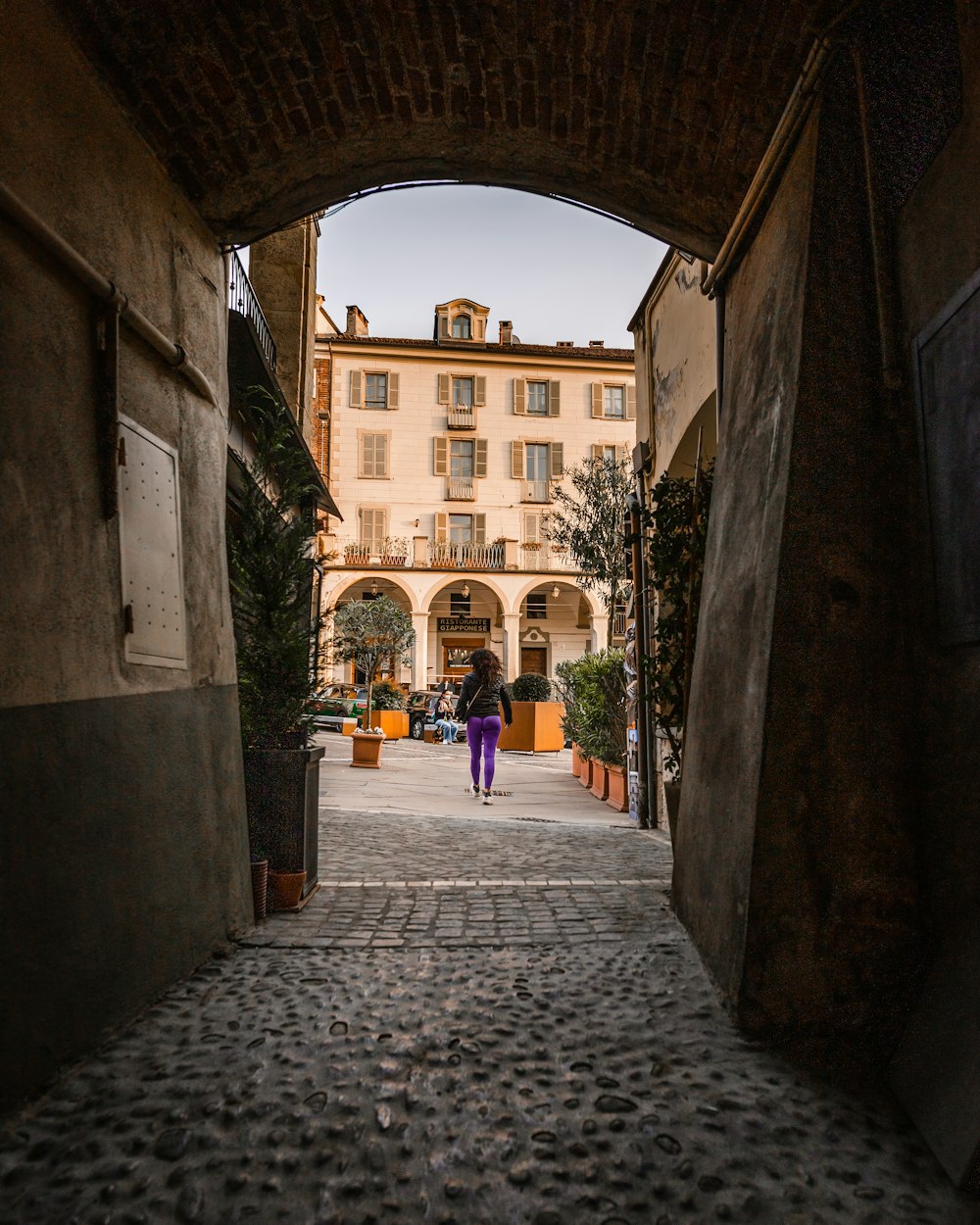 persone che camminano su un sentiero di cemento grigio tra edifici in cemento durante il giorno