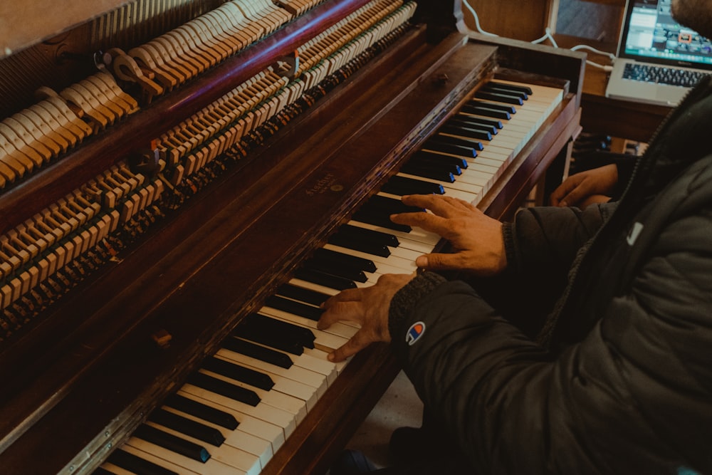 person playing brown upright piano