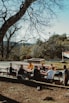 Outdoor gathering of a small group enjoying a picnic in a sunny park.