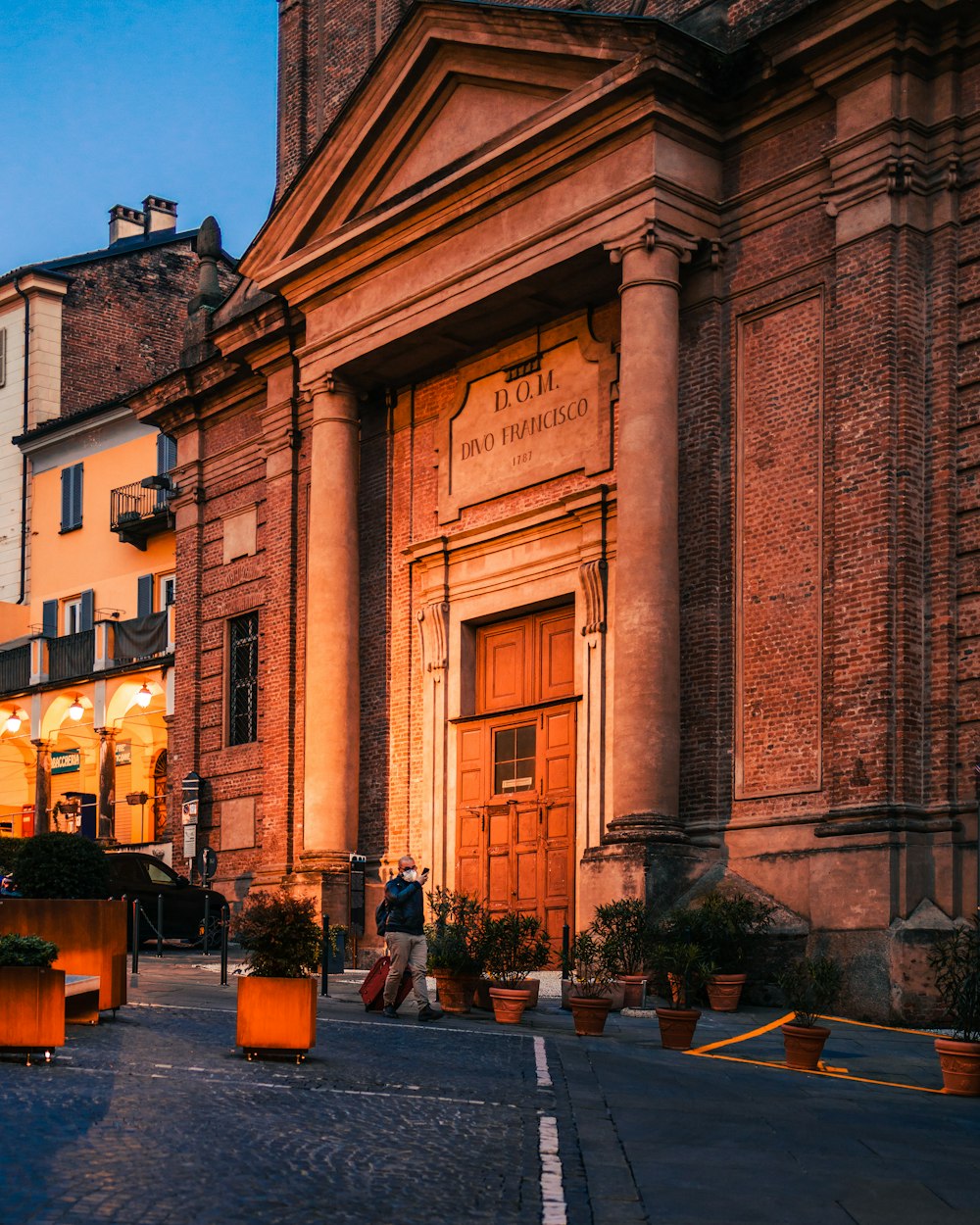 persone che camminano sul marciapiede vicino a un edificio in cemento marrone durante il giorno