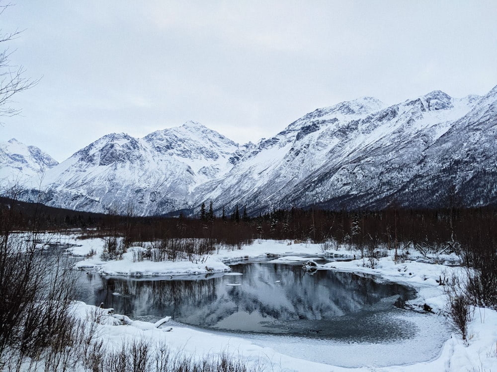 snow covered mountain near body of water during daytime