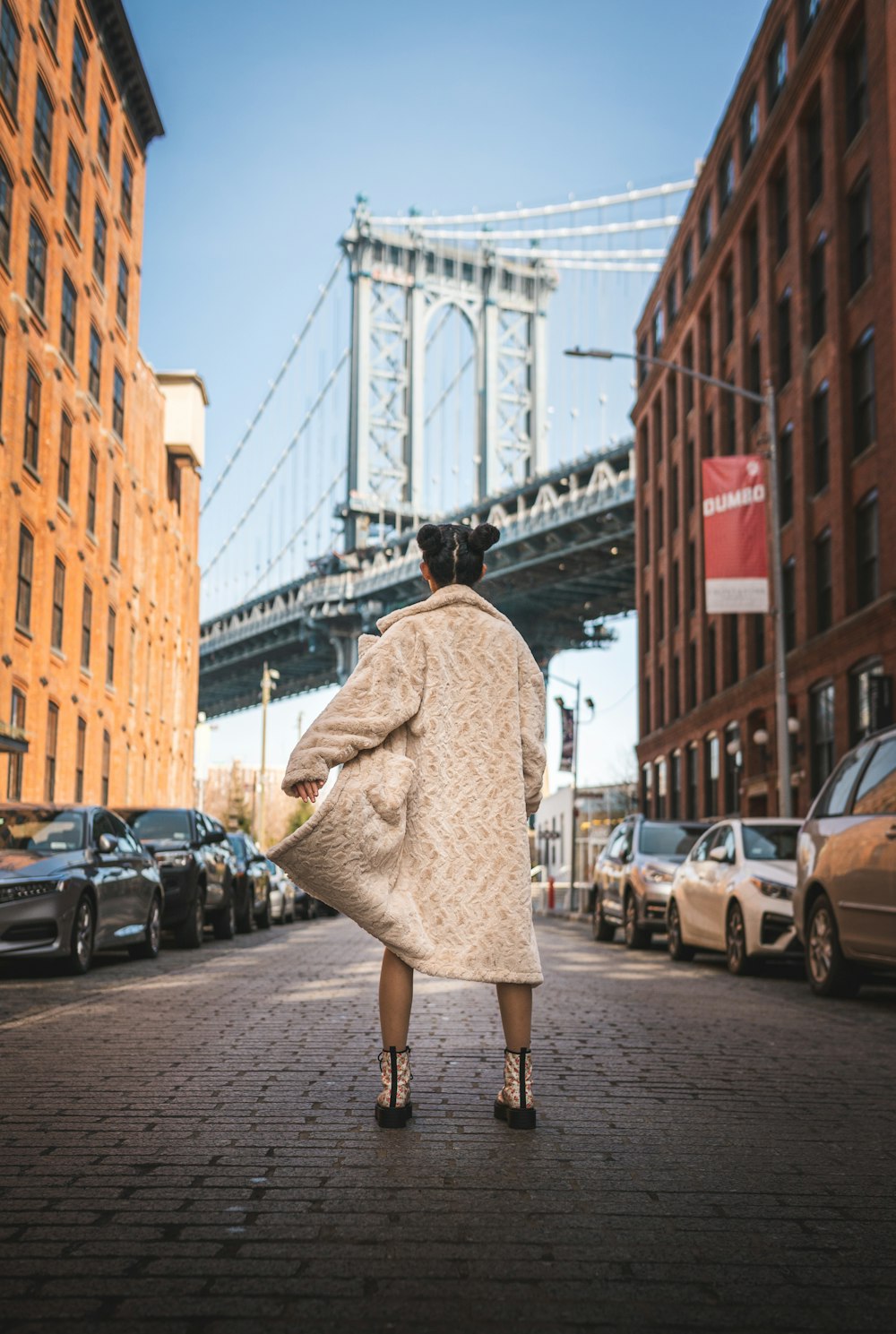 woman in beige coat walking on sidewalk during daytime