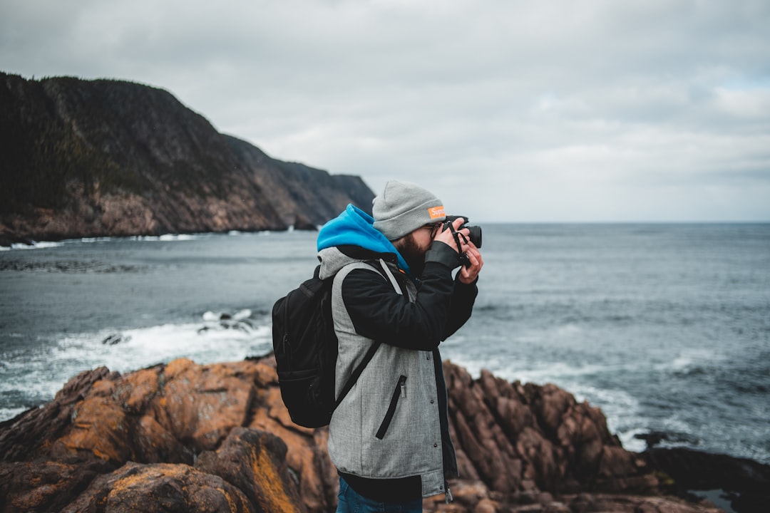 man in black jacket taking photo of sea during daytime