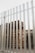 Tall, neatly stacked wooden pallets are visible behind a tall metal fence with vertical bars. The pallets are arranged in an orderly fashion and there is an industrial building visible in the background.