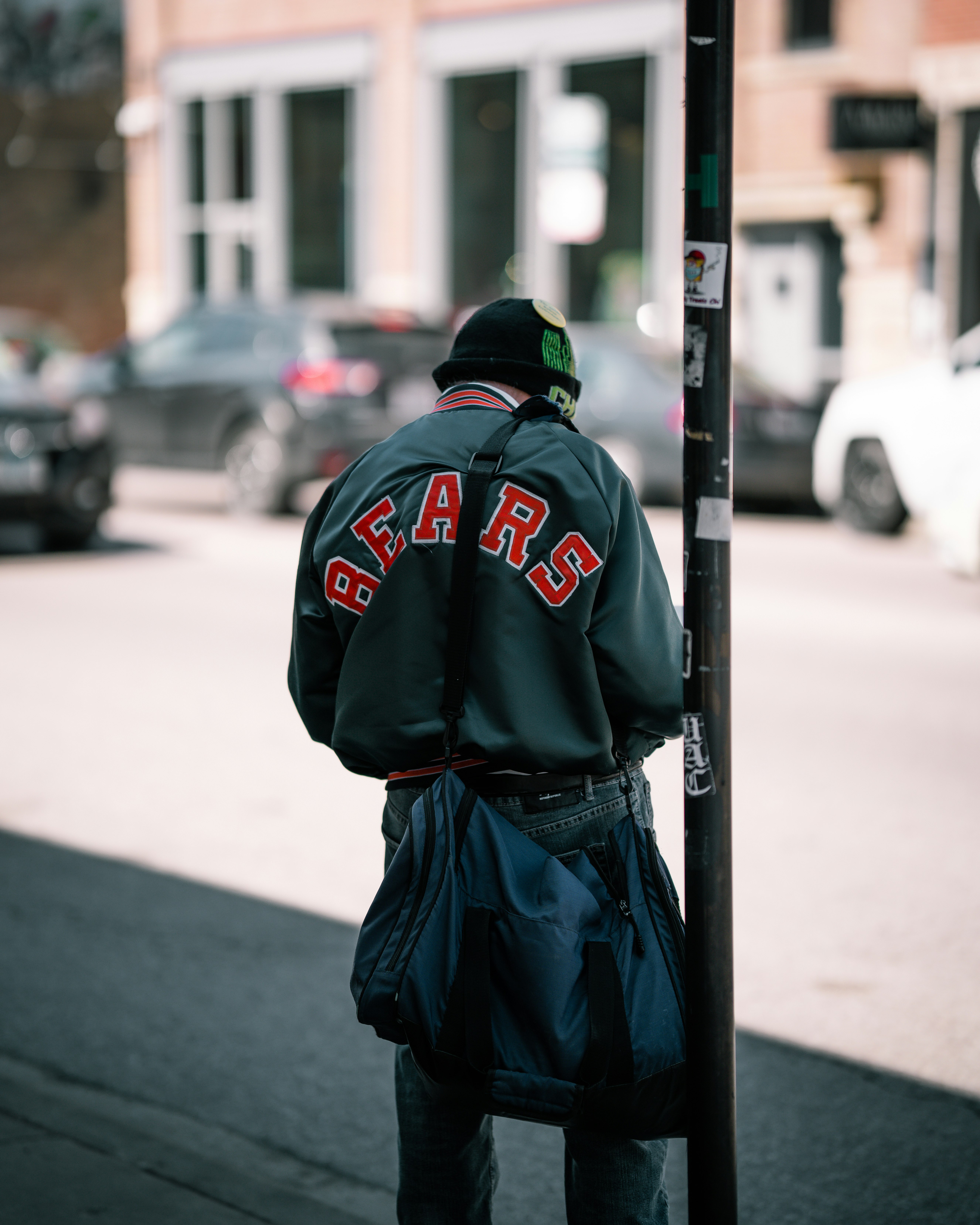man in black and red hoodie standing on sidewalk during daytime