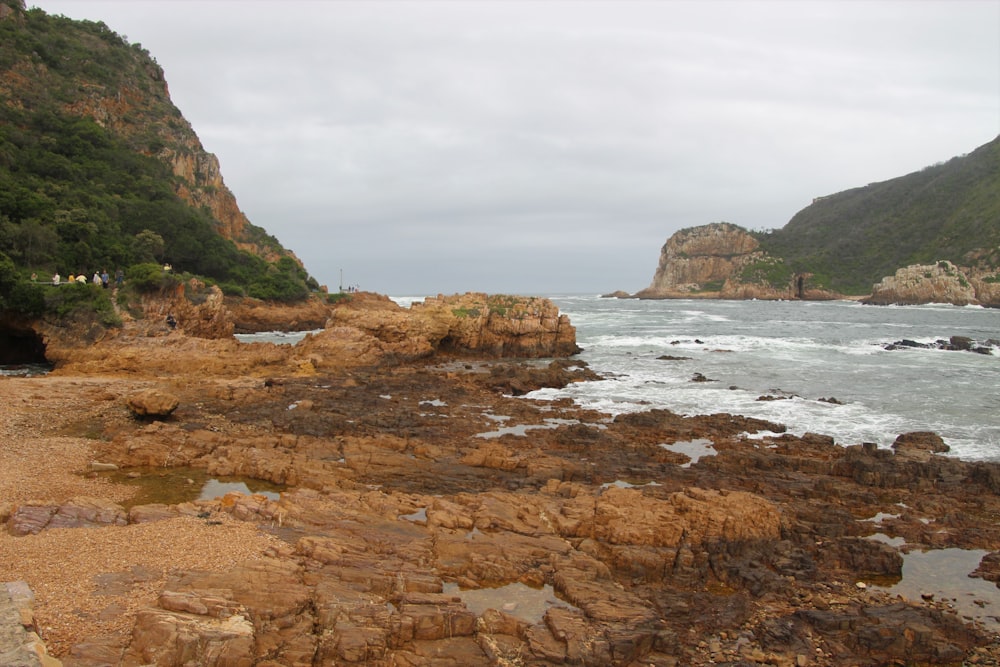 brown rock formation beside body of water during daytime