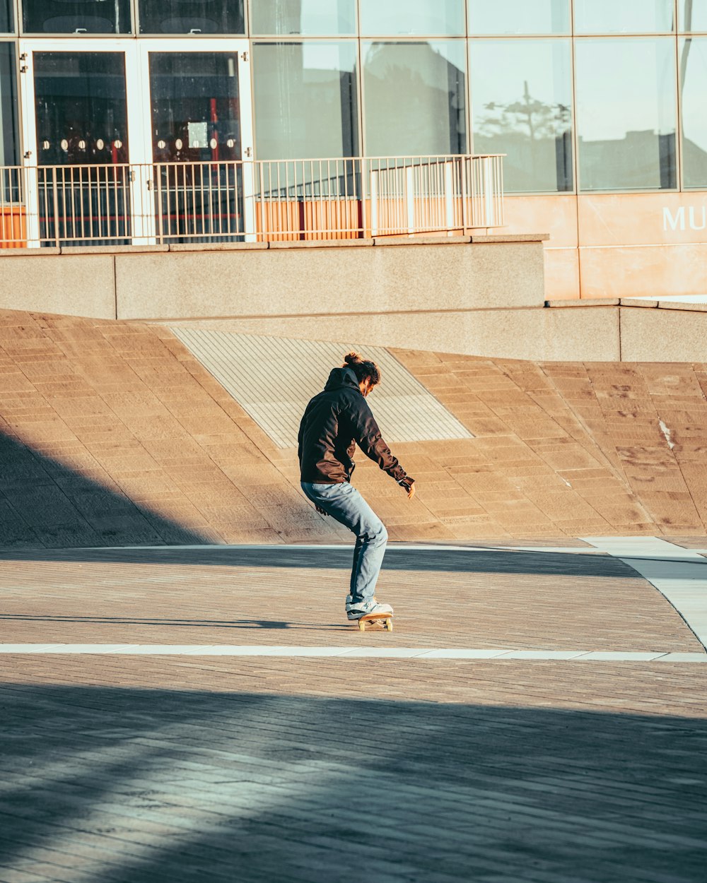 man in black hoodie and blue denim jeans walking on gray concrete road during daytime