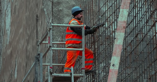 man in red jacket and blue cap standing on ladder