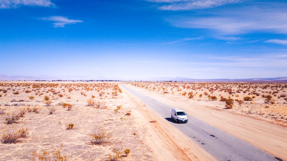 white car on brown field under blue sky during daytime