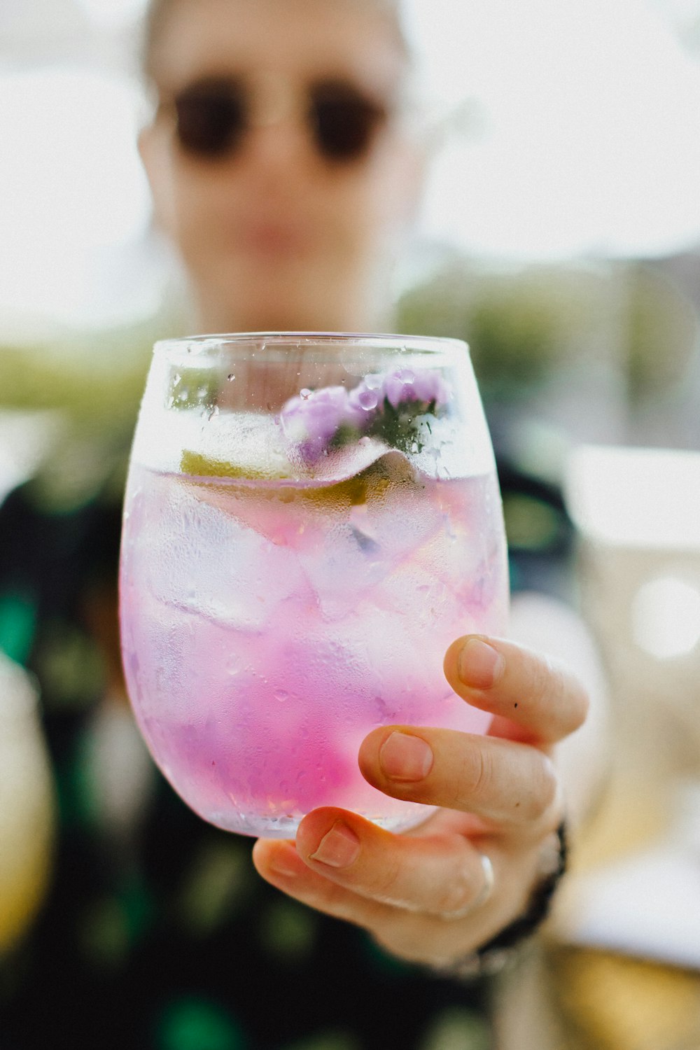 pessoa segurando copo transparente com líquido rosa