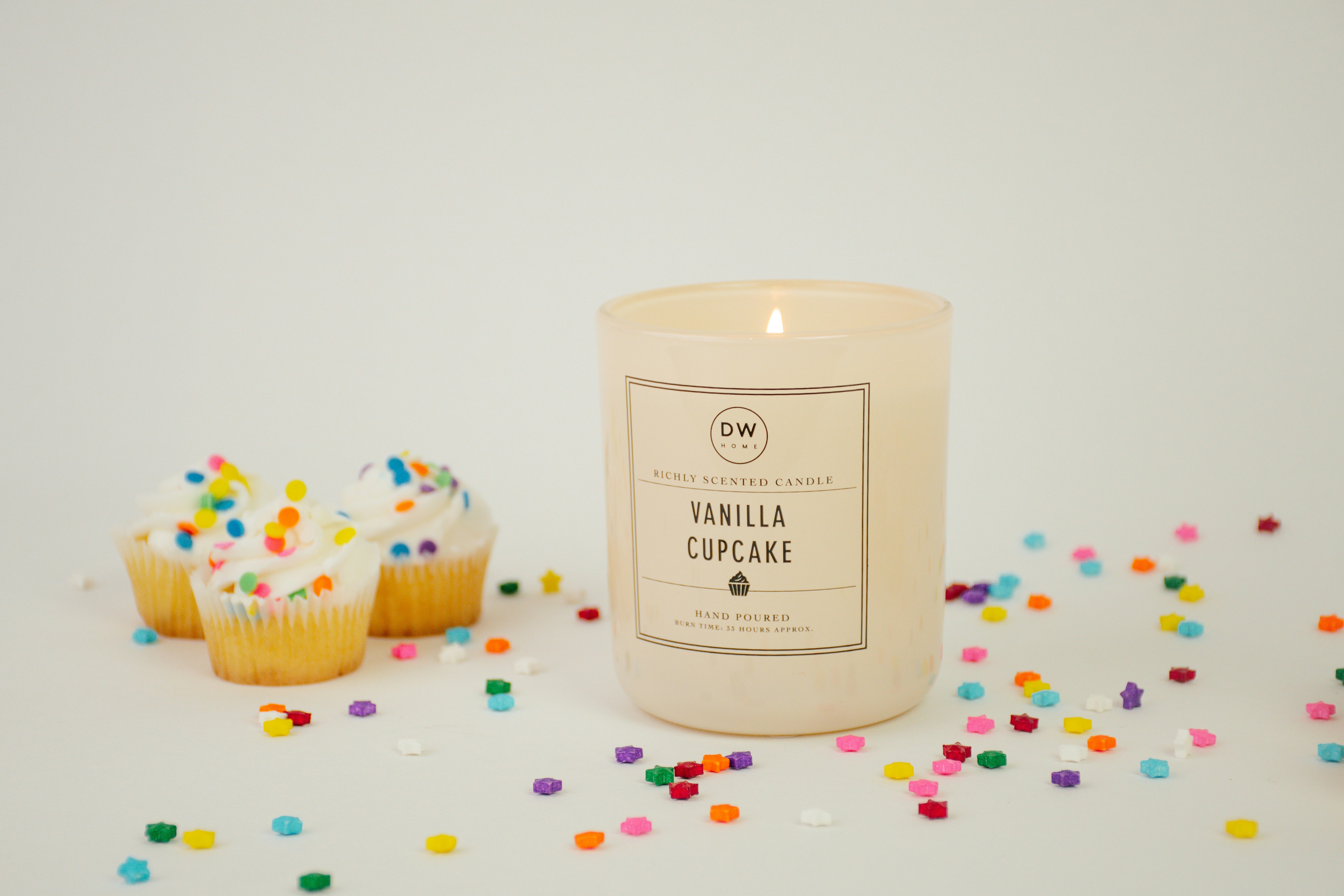 Vanilla cupcake candle lit with birthday scene. Cupcakes and confetti are sprinkled around the candlelight on a white studio backdrop. I'd love to see how you use this photo! Tag me on social media @mandacreatespretty.