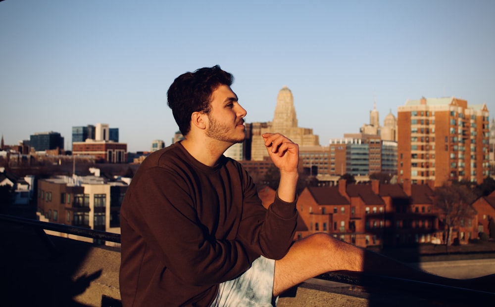 man in brown sweater smoking cigarette during daytime