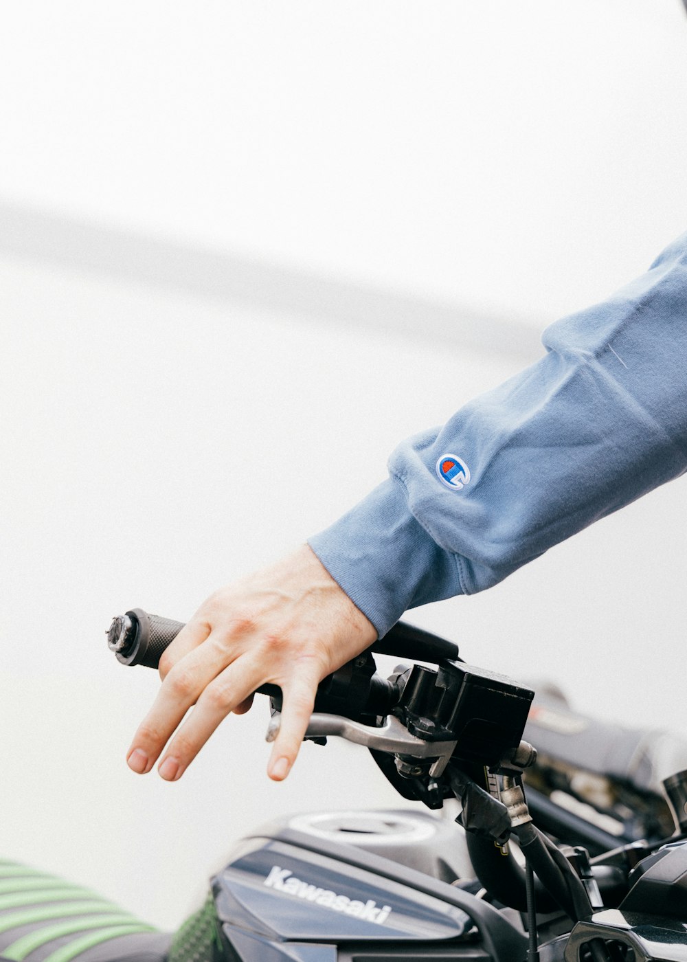person in blue long sleeve shirt holding black and gray bicycle handle bar