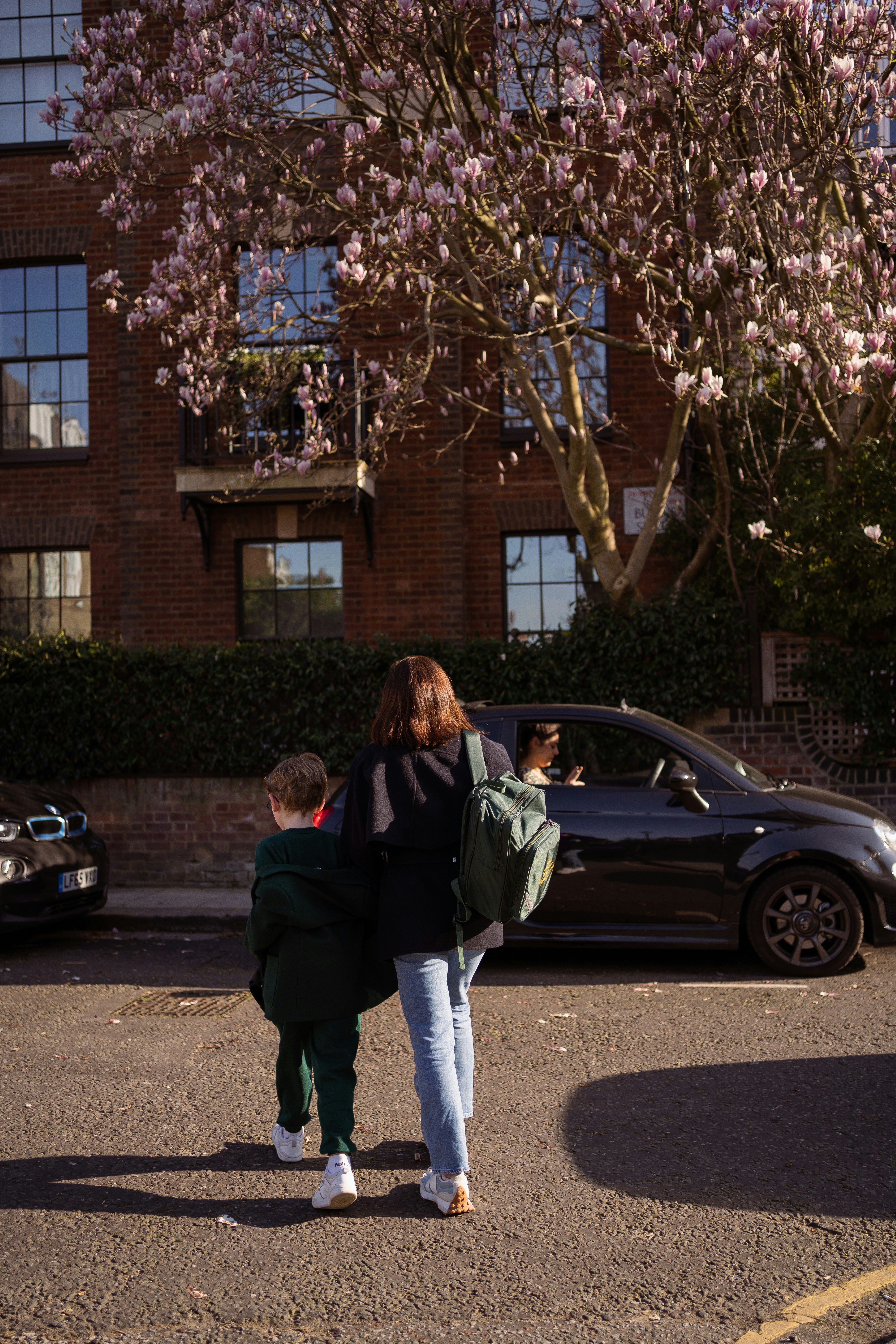 woman in black jacket standing beside black sedan during daytime