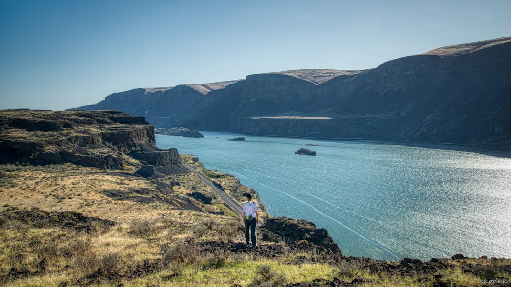 person standing on rock formation near body of water during daytime