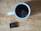Close-up of a steaming cup of coffee next to a box of assorted chocolates on a wooden table.