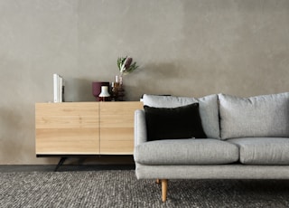 gray cushion couch beside brown wooden cabinet