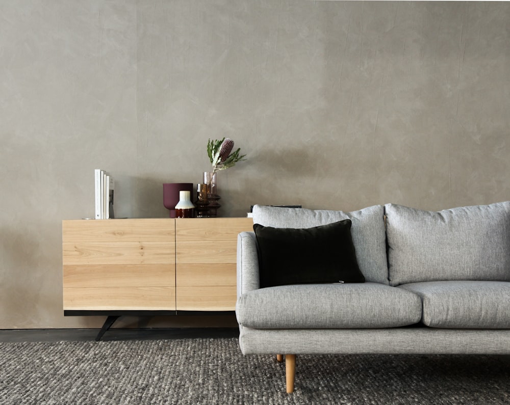 gray cushion couch beside brown wooden cabinet