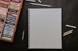 white spiral notebook beside white pen
