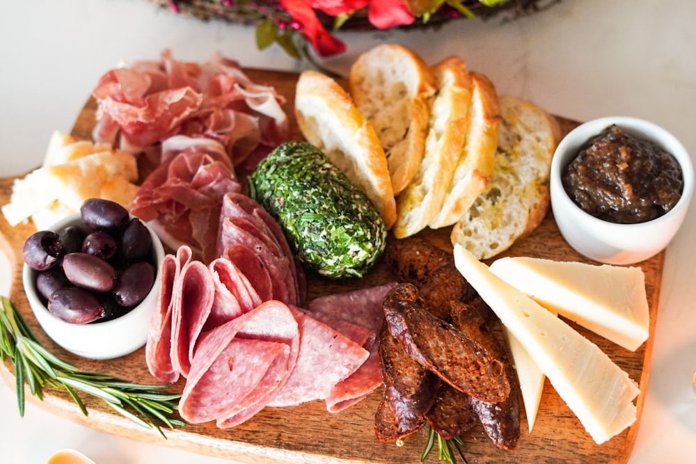 Affettata di carne con verdure e pane su tagliere di legno marrone