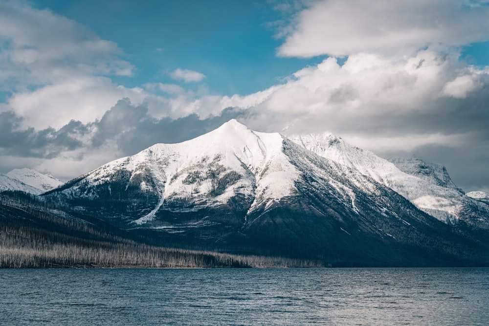 snow covered mountain near body of water during daytime