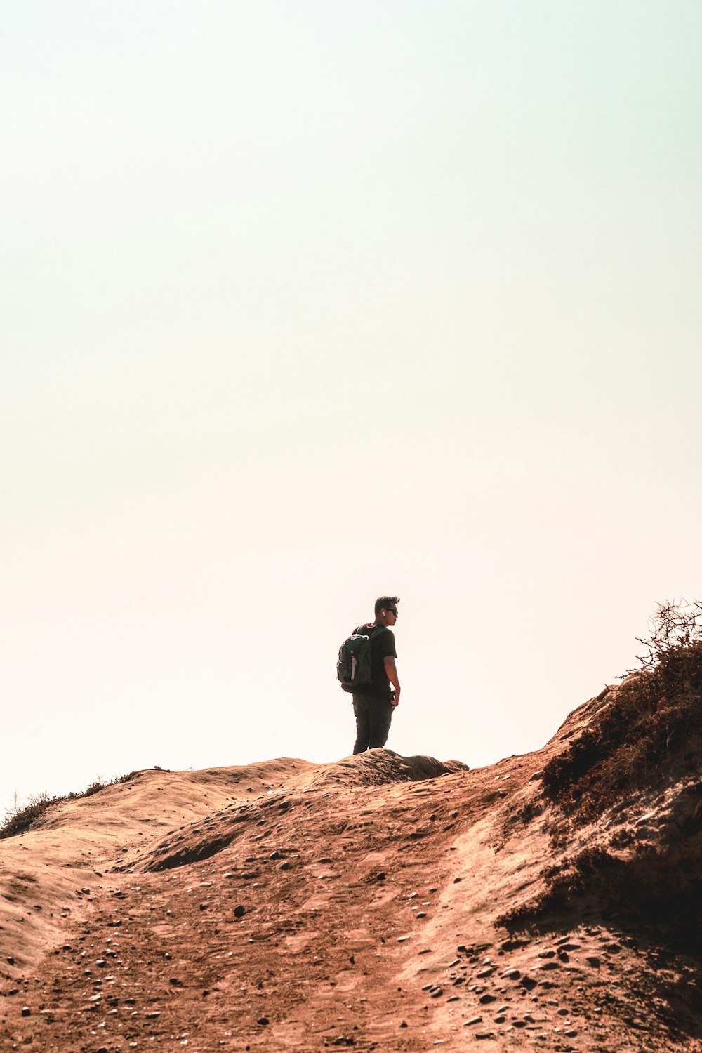 man in black jacket standing on brown rock during daytime