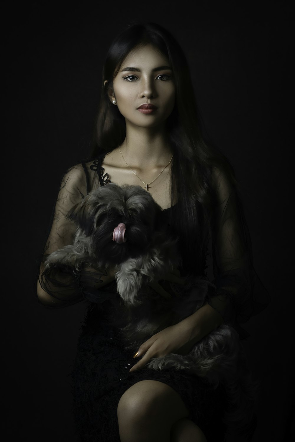 woman in brown sleeveless top holding black and white long coated small dog