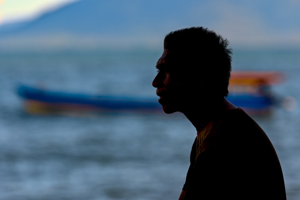 man in red crew neck shirt standing near body of water during daytime