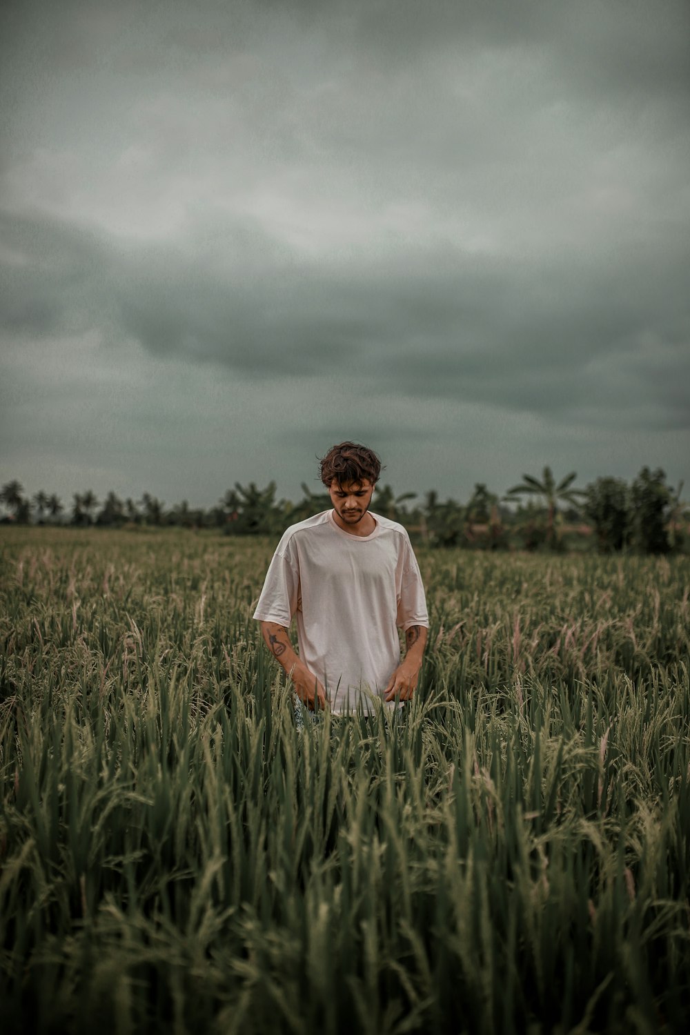 man in white crew neck t-shirt standing on green grass field during daytime