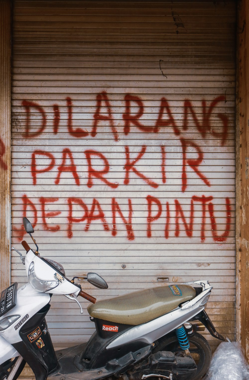 white and black motor scooter parked beside white and red wall