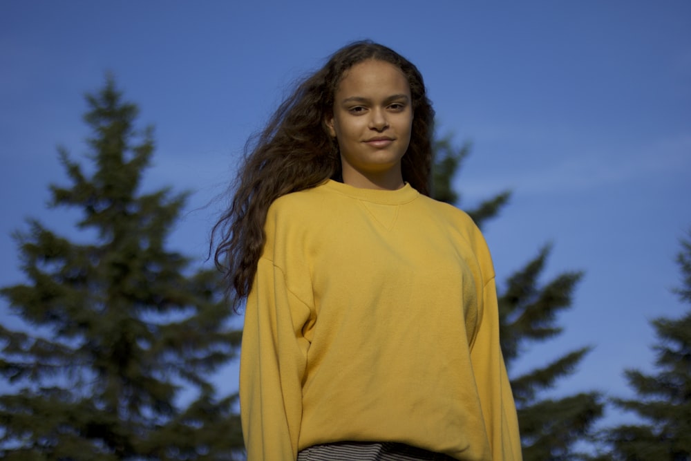 Femme en pull à col roulé jaune debout sous le ciel bleu pendant la journée