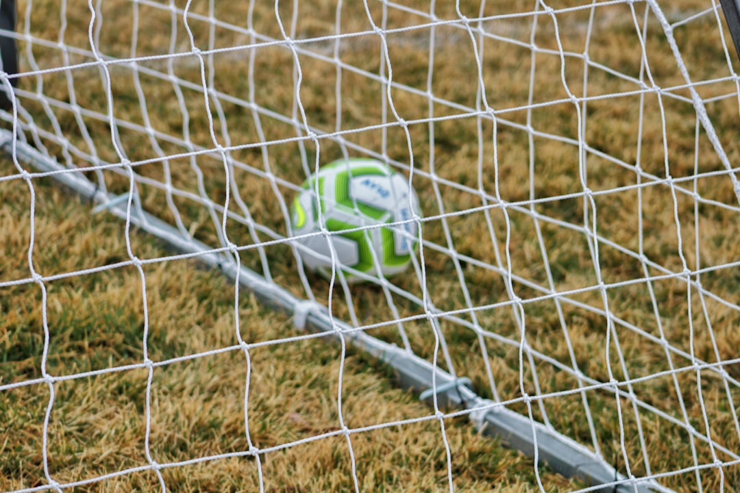 green and black soccer ball on brown field