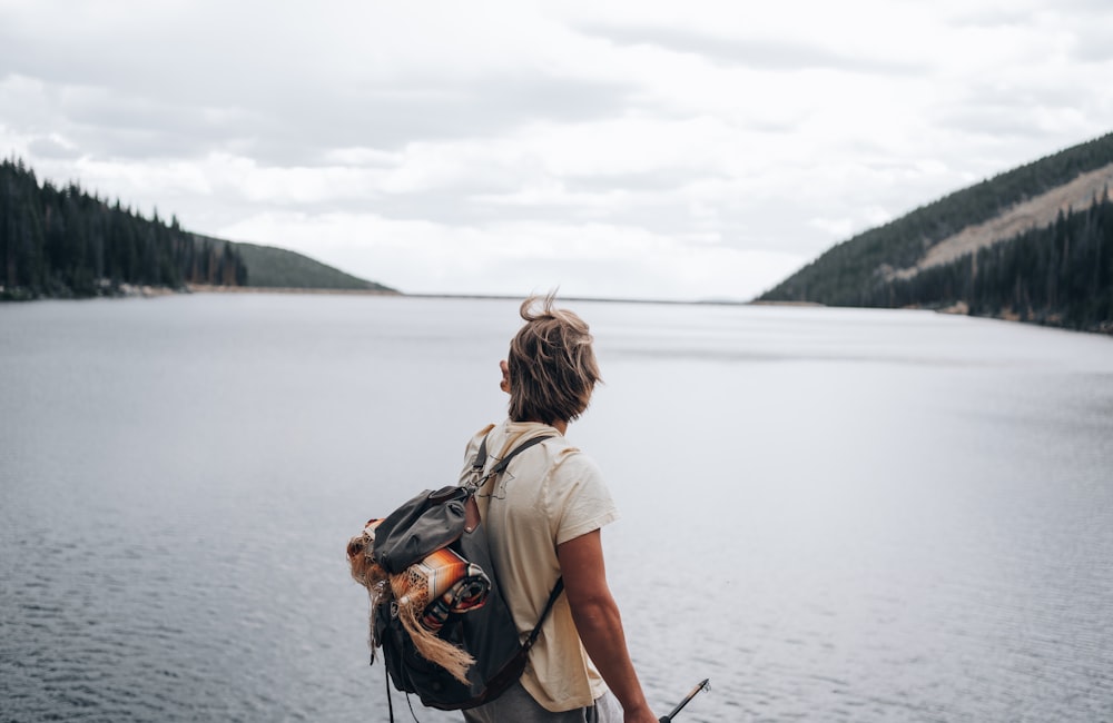 woman in brown t-shirt and black backpack standing on lake during daytime