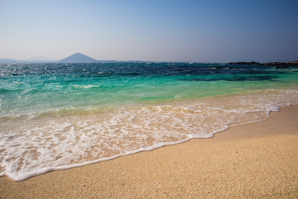 sea waves crashing on shore during daytime