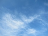 Soft pale blue sky with wispy white clouds drifting gently.