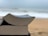 A close-up view of two stacked books with slightly curved pages, set against a blurred beach and ocean background.