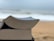 A close-up view of two stacked books with slightly curved pages, set against a blurred beach and ocean background.