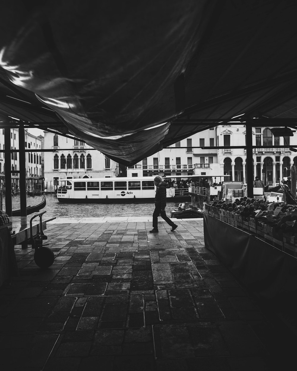 grayscale photo of man walking on sidewalk