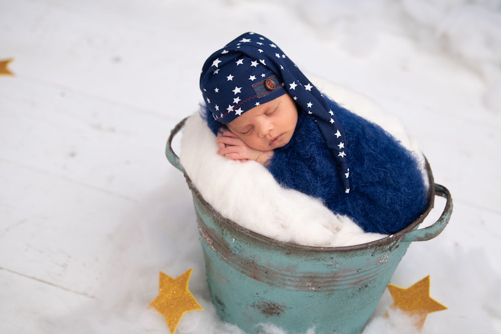 child in blue and white jacket in blue bucket