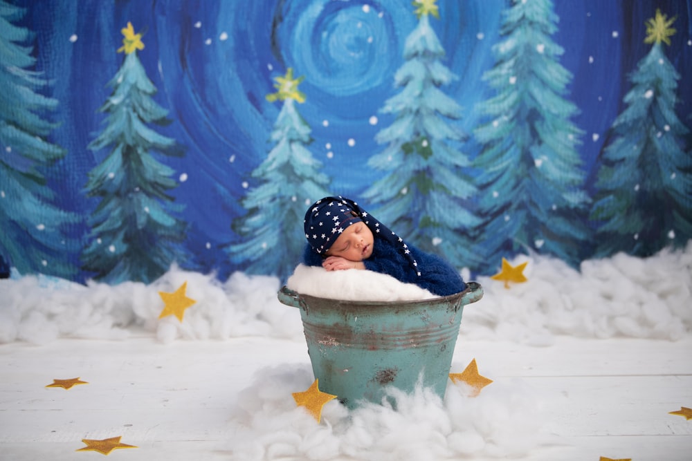 girl in blue jacket in white plastic bucket on snow covered ground