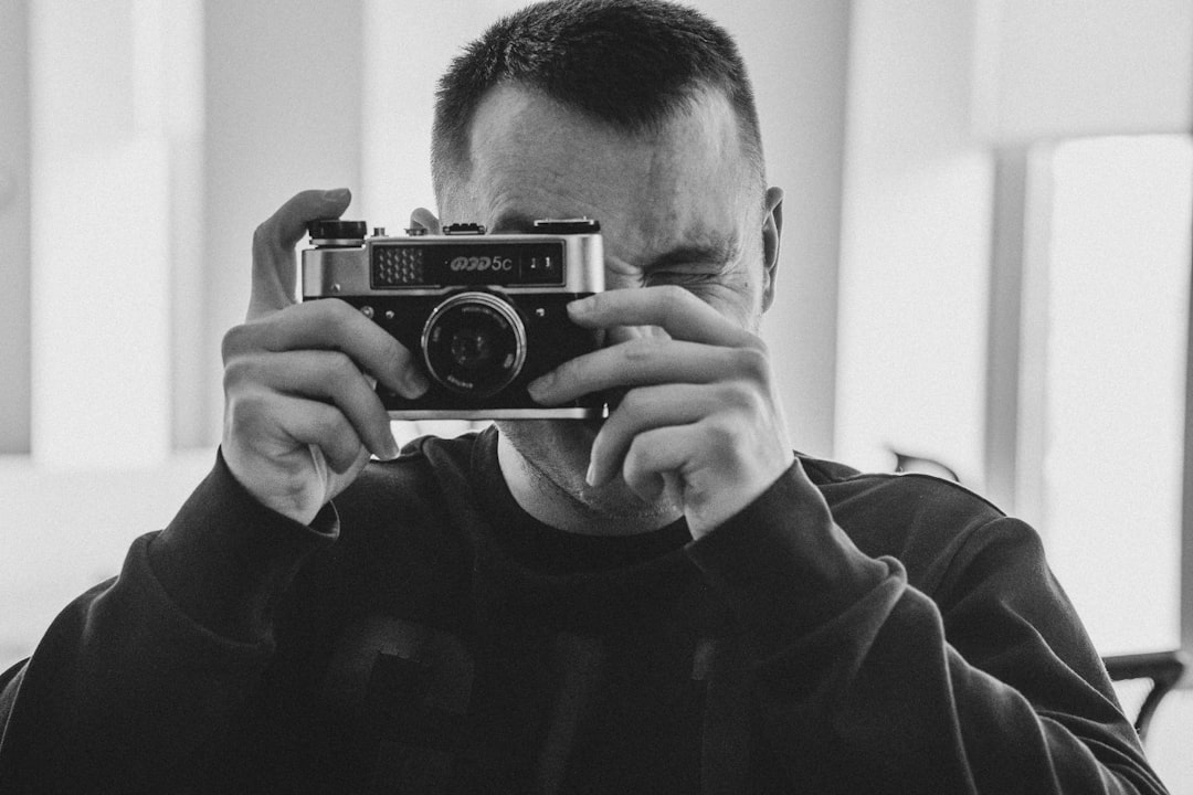 grayscale photo of man holding camera