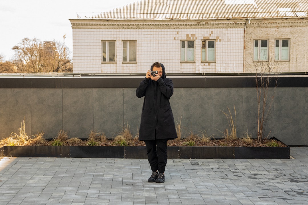 woman in black coat standing on gray brick floor