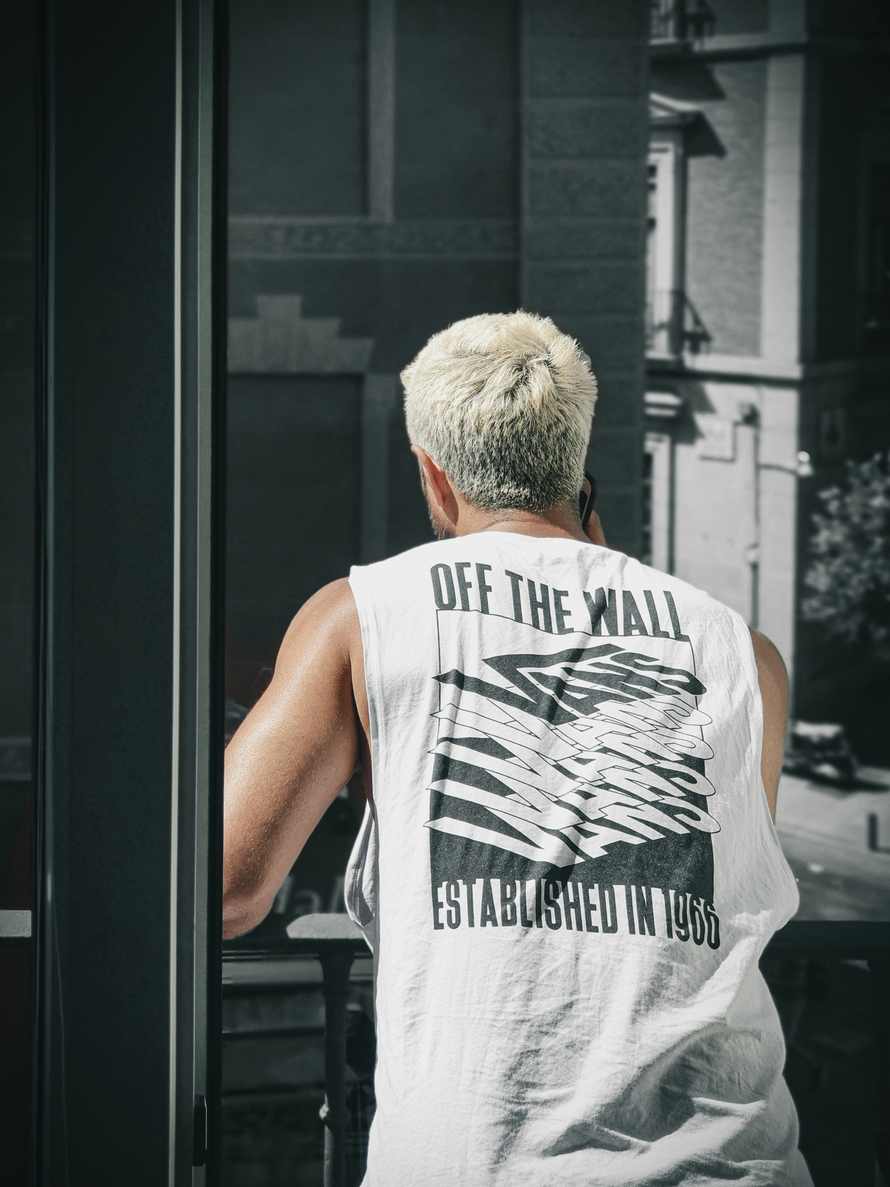 man in white and black tank top standing beside glass window