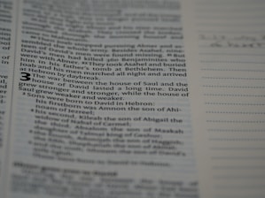 A close-up of a page from a book, featuring a passage discussing the war between the house of Saul and the house of David. The text is in English and appears in a structured format similar to bible verses. The number 3 is prominently displayed, suggesting the beginning of a chapter or section. The background includes lined spaces, possibly for notes.