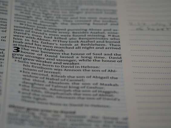 A close-up of a page from a book, featuring a passage discussing the war between the house of Saul and the house of David. The text is in English and appears in a structured format similar to bible verses. The number 3 is prominently displayed, suggesting the beginning of a chapter or section. The background includes lined spaces, possibly for notes.