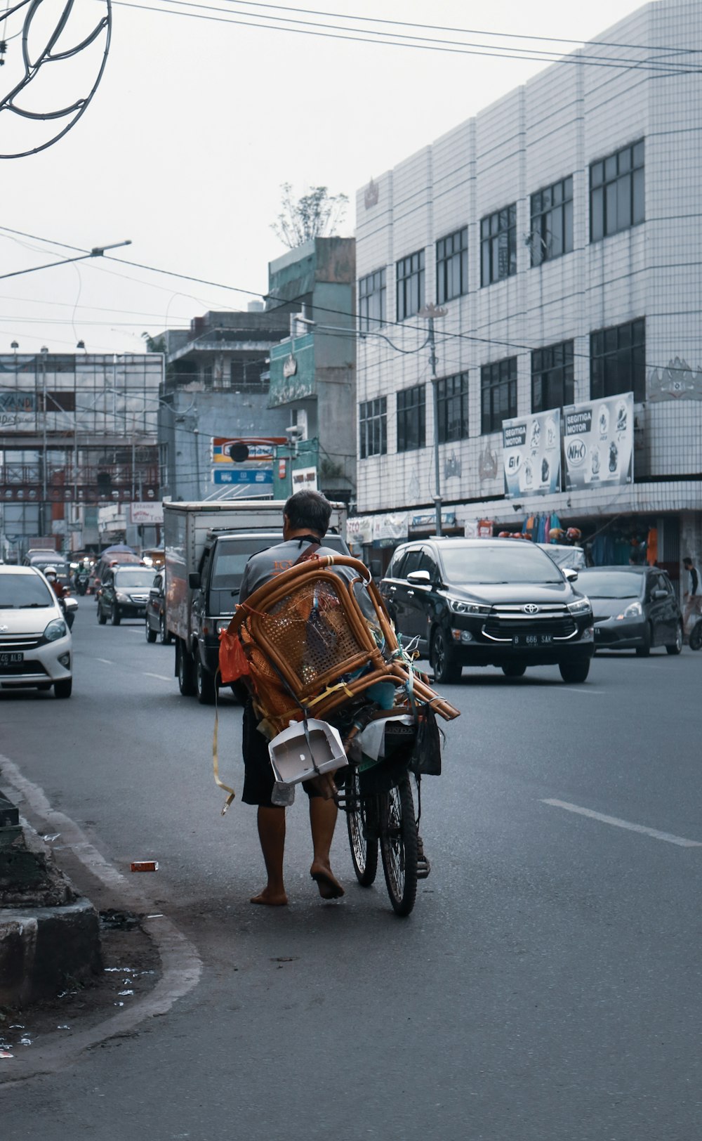 homme en chemise blanche et sac à dos marron faisant du vélo sur la route pendant la journée
