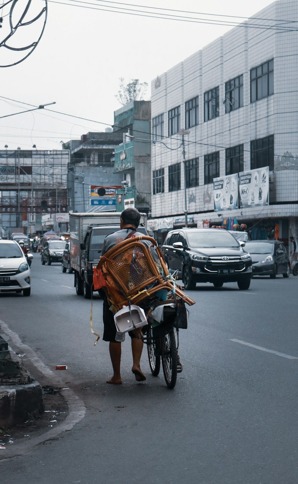 Hombre con camisa blanca y mochila marrón montando en bicicleta en la carretera durante el día